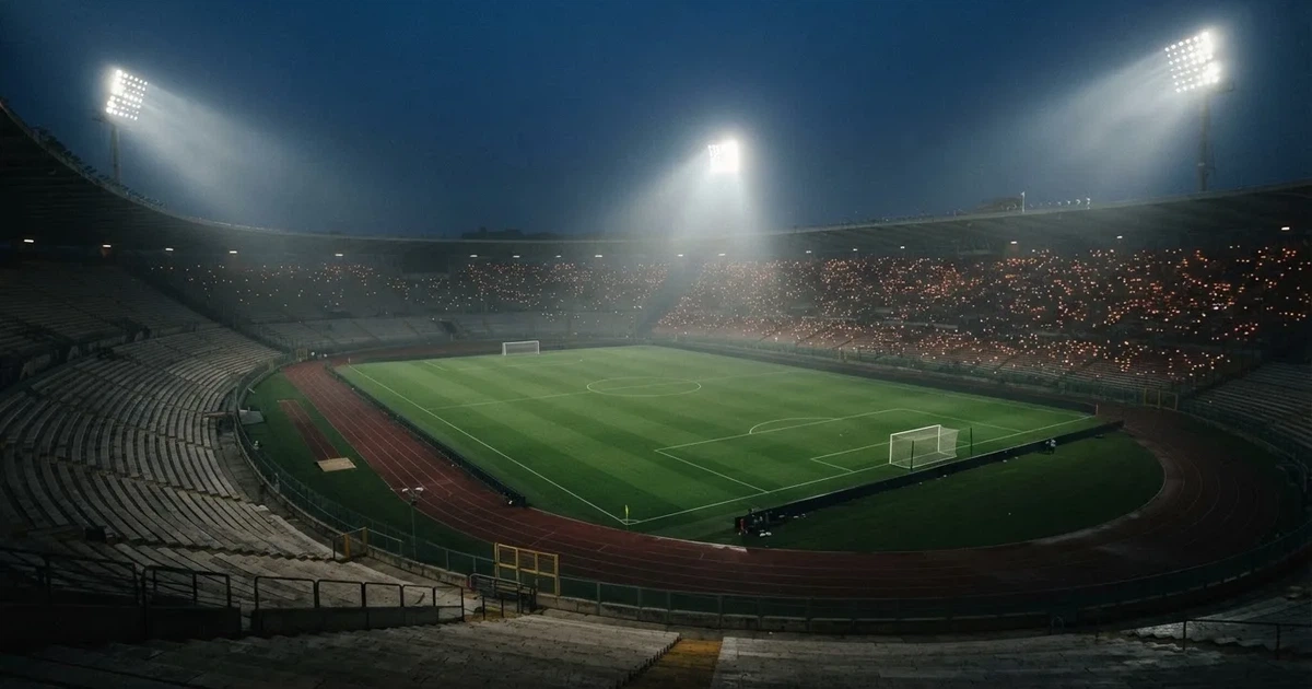 Ein leeres Stadion unter Flutlicht aus großer Entfernung gesehen, Dunst liegt über dem Rasen, die Tribünen sind nur als Lichtpunkte erkennbar.