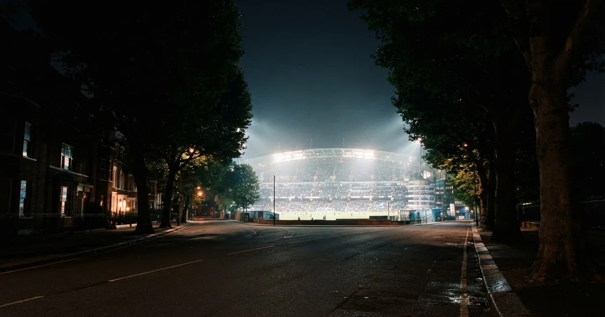 Ein Fußballstadion bei Nacht aus großer Entfernung, hell erleuchtet unter Flutlicht, davor eine dunkle Straße und Bäume.